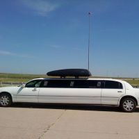 Large white stretch limo parked at small airport